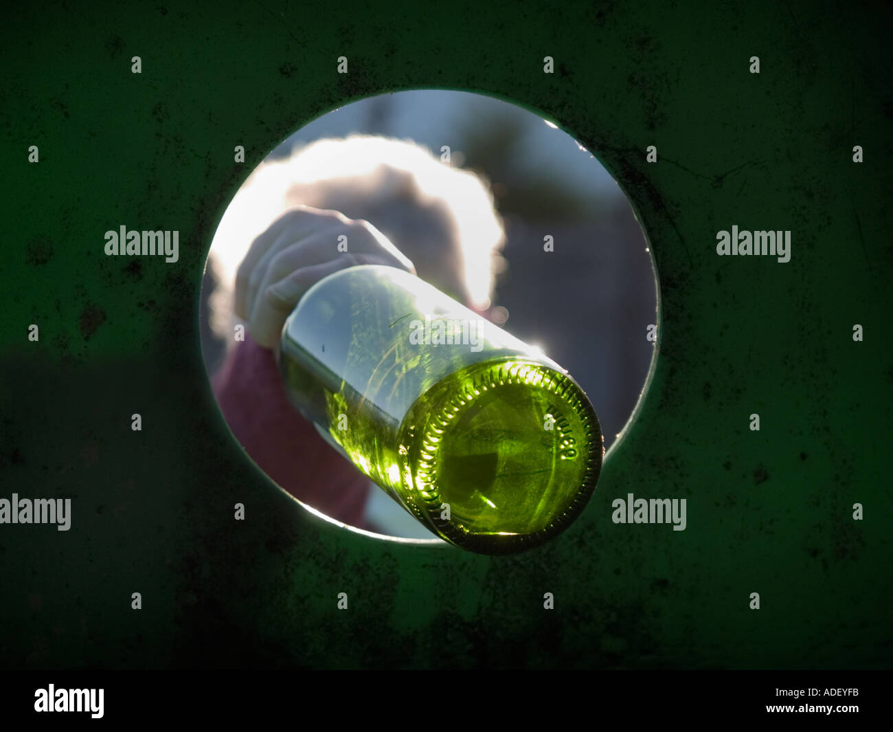 Bottiglia in vetro verde il contenitore di riciclaggio con capelli grigi lady mettere verde bottiglia attraverso il foro dello scomparto dall'interno. Inghilterra Regno Unito Gran Bretagna Foto Stock