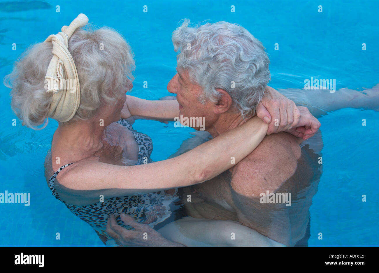 Coppia di anziani abbracciando in piscina Foto Stock