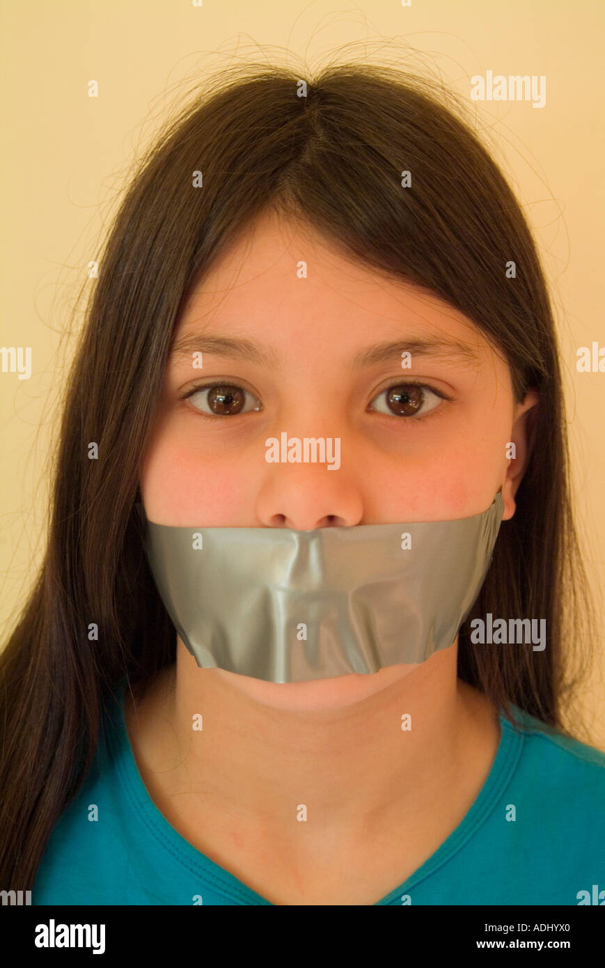 Ragazza giovane con nastro sopra la bocca per illustrare la soppressione della libertà di parola Foto Stock