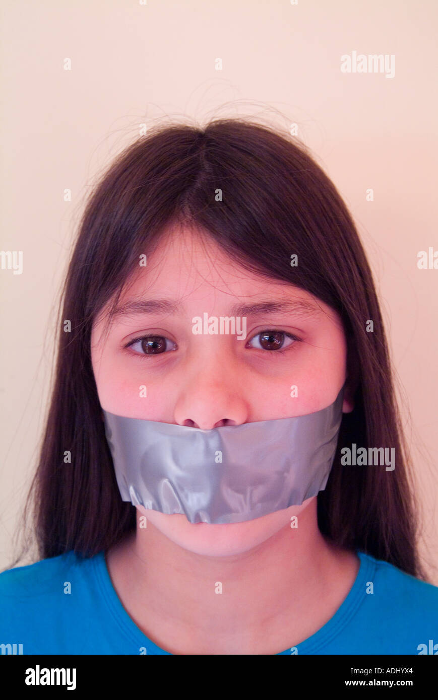 Ragazza giovane con nastro sopra la bocca per illustrare la soppressione della libertà di parola Foto Stock