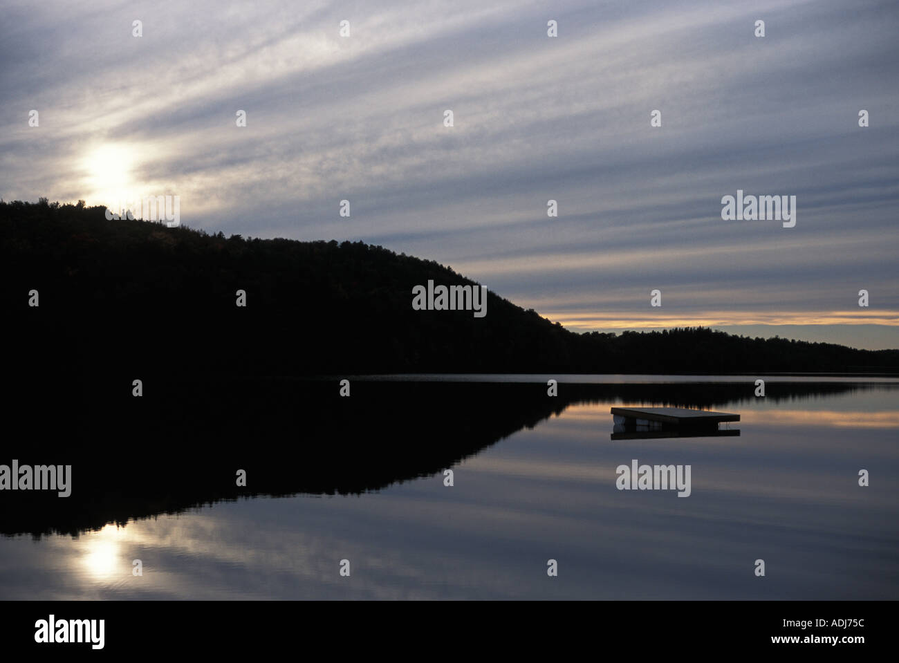 Pontile galleggiante sul lago calmo acqua al tramonto con collina boscosa in background New Brunswick Canada Foto Stock