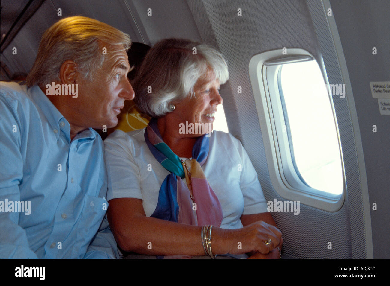 Seniorenpaar im Flugzeug aus dem Fenster schauend Foto Stock