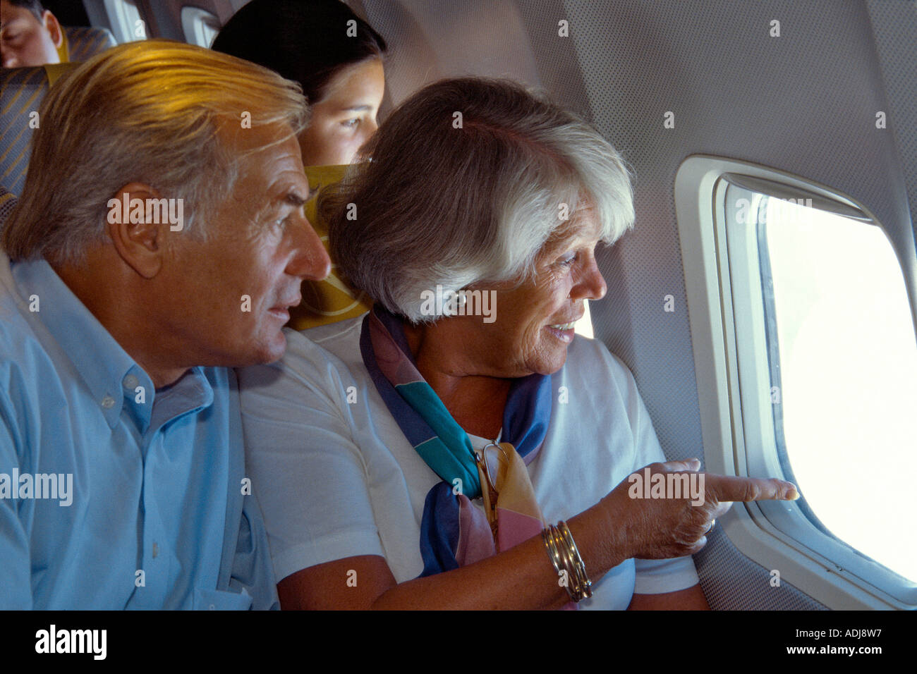 Seniorenpaar im Flugzeug aus dem Fenster schauend Foto Stock