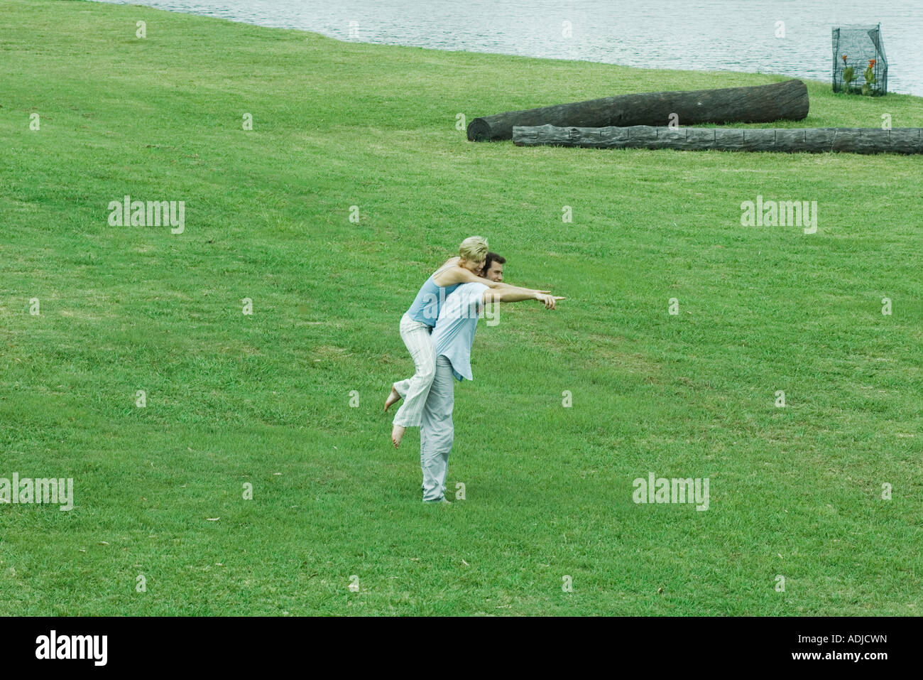 Matura sul prato, uomo donna azienda piggyback, puntando a distanza Foto Stock