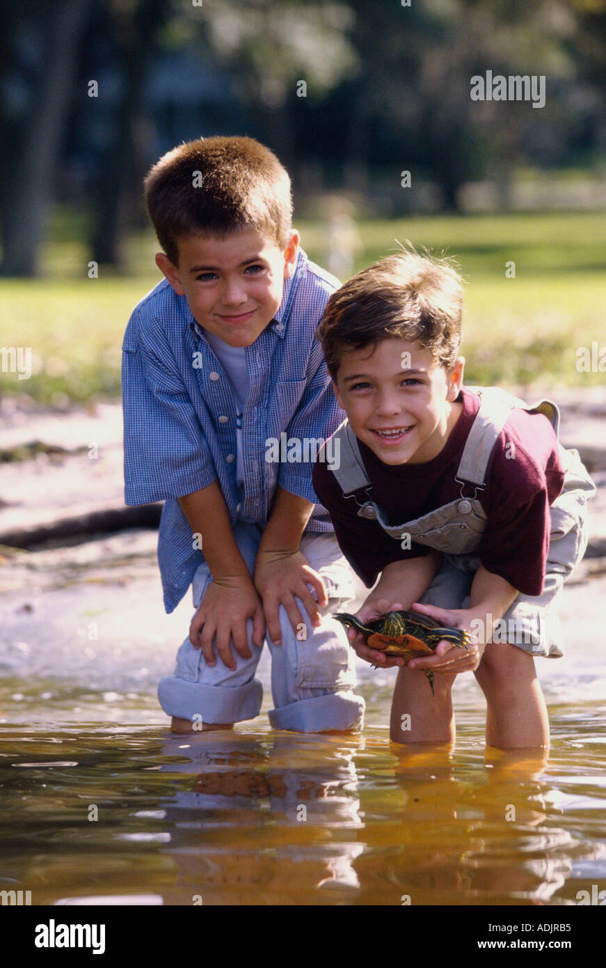 Ritratto di due ragazzi in piedi in acqua holding una tartaruga Foto Stock