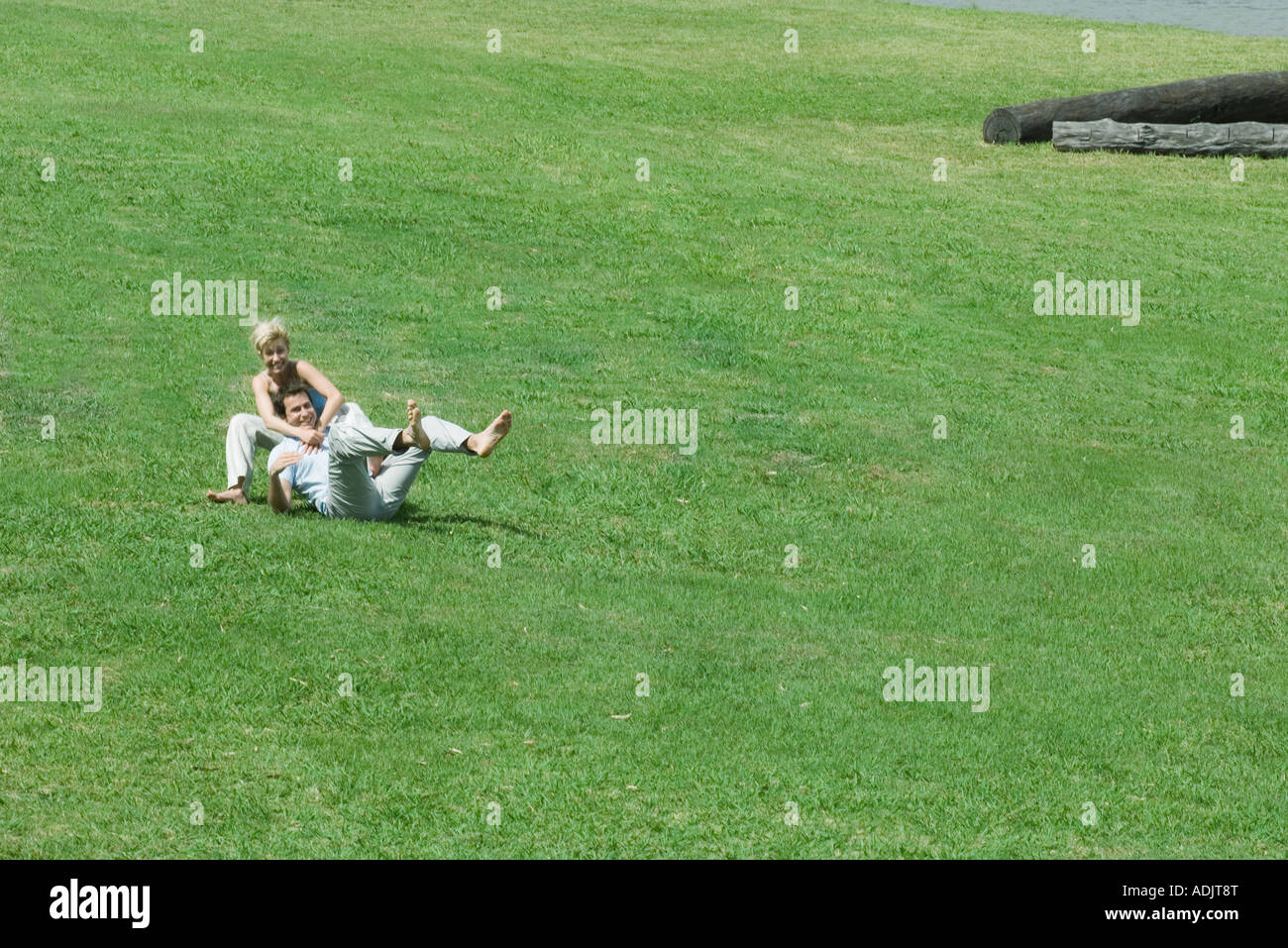 Giovane seduto sull'erba insieme, uomo Pendente ritornare sulla donna Foto Stock