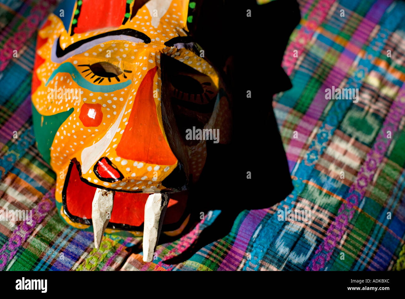 Guatemala danza in legno maschera di una Jaguar contro multicolore tessuto Guatemala Chichicastenango mercato Guatemala Foto Stock