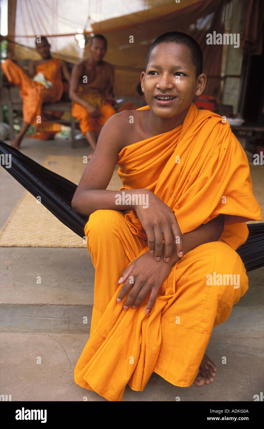 Felice giovane monaco Buddista nel suo giallo vesti seduti in un amaca Cambogia Foto Stock