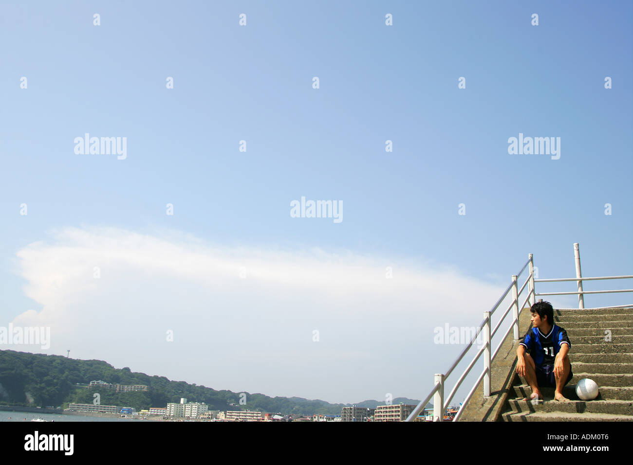 Giovane giocatore di calcio seduto su una rampa di scale Foto Stock