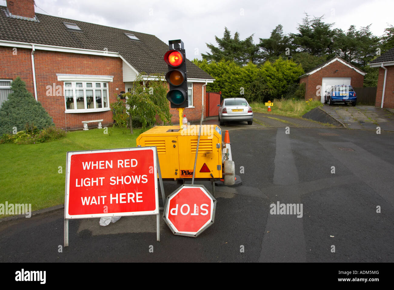 Quando la spia rossa mostra aspettare qui segni di arresto accanto a semafori portatili sul generatore in ambito residenziale cul de sac newtownabbey Foto Stock