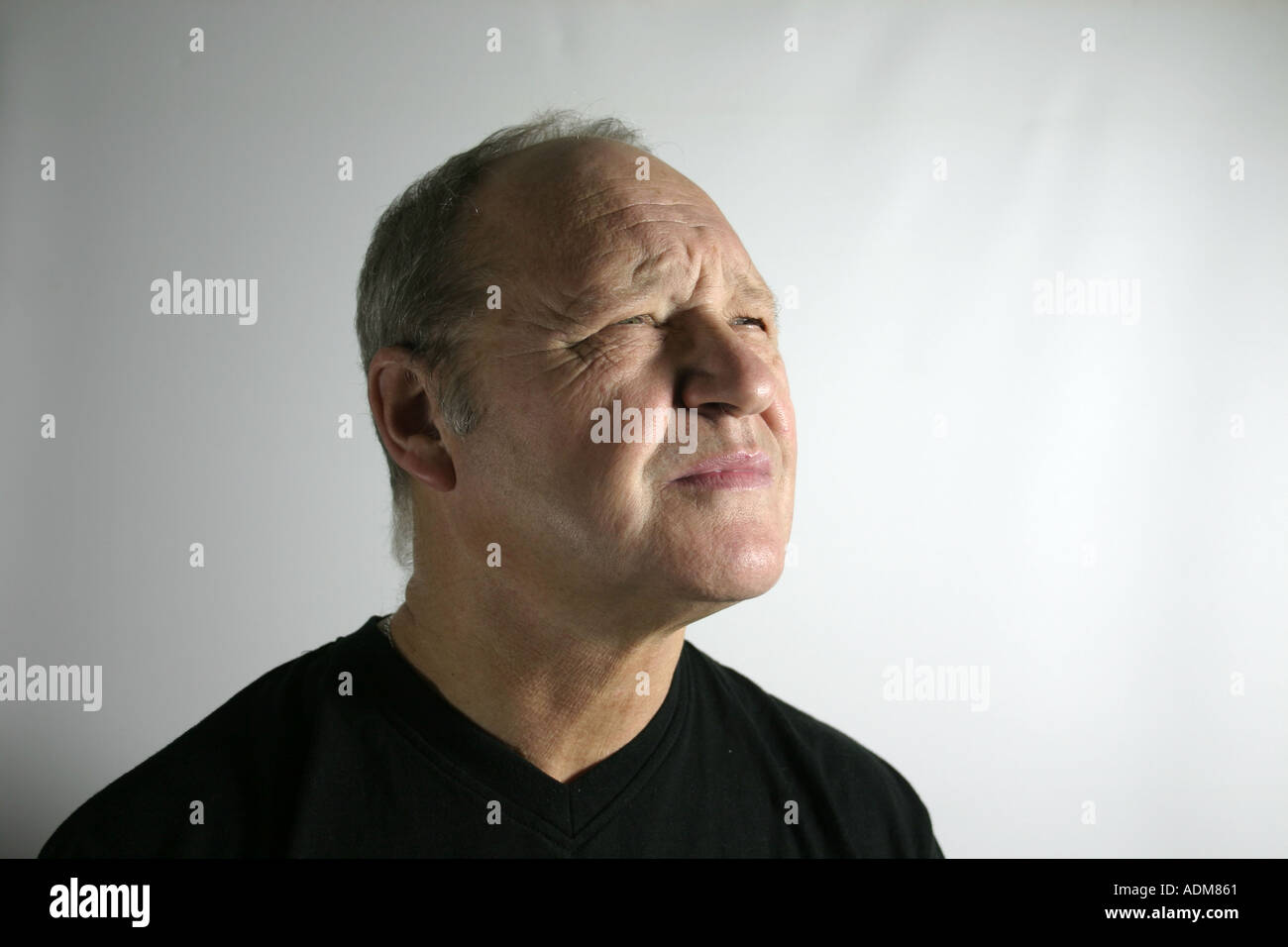 L uomo nella sua anni sessanta squints a qualcosa in distanza Foto Stock
