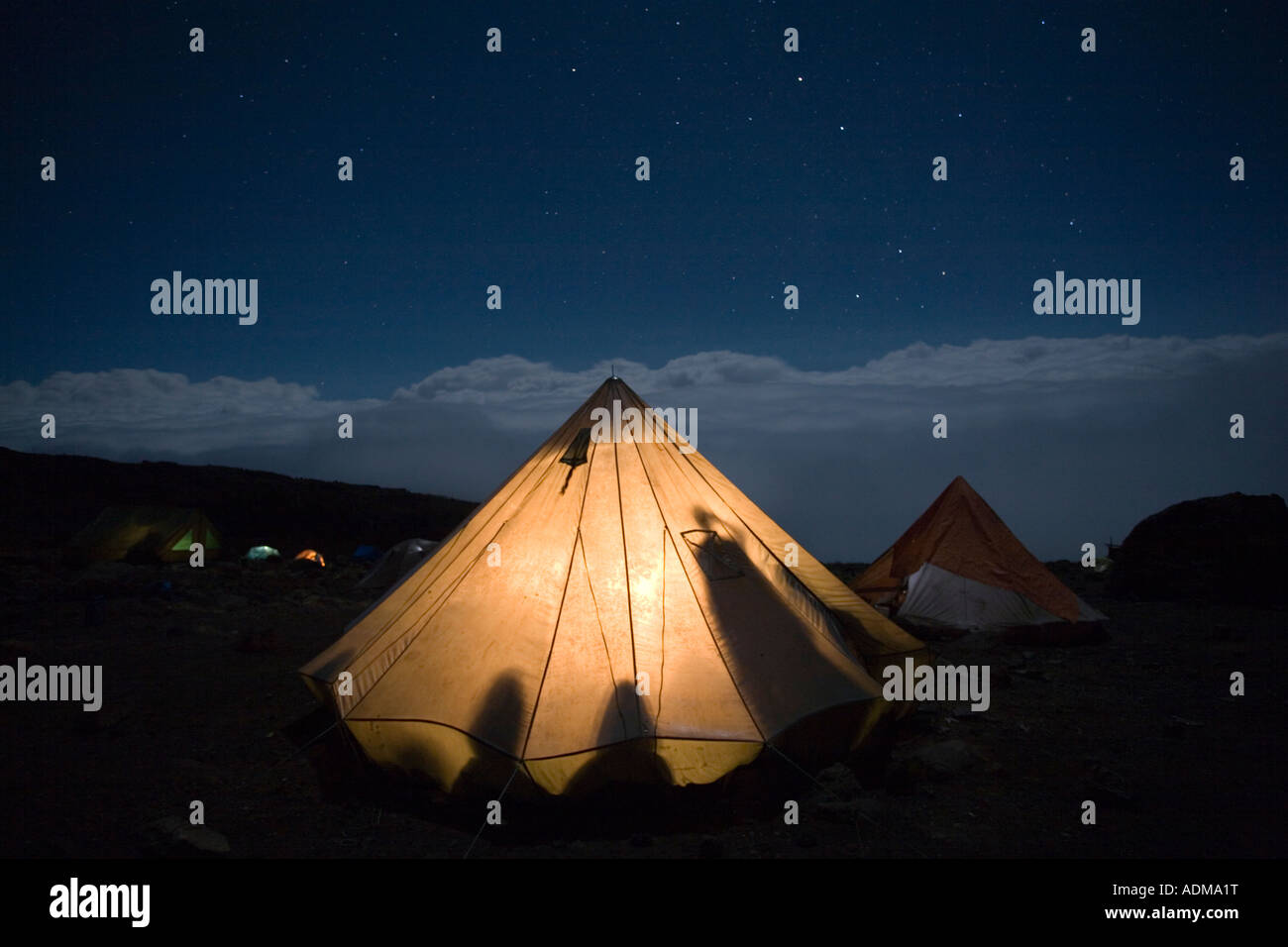 Africa Tanzania Parco Nazionale del Kilimanjaro Signor Arrampicata parti tende glow contro il cielo notturno a Karanga Camp Foto Stock