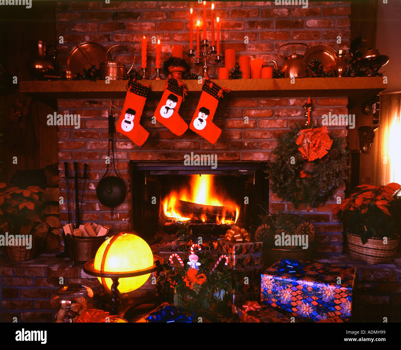 Camino di Natale ancora vita mostrando blazing focolare in mattoni con calze poinsettia e articoli di festa Foto Stock