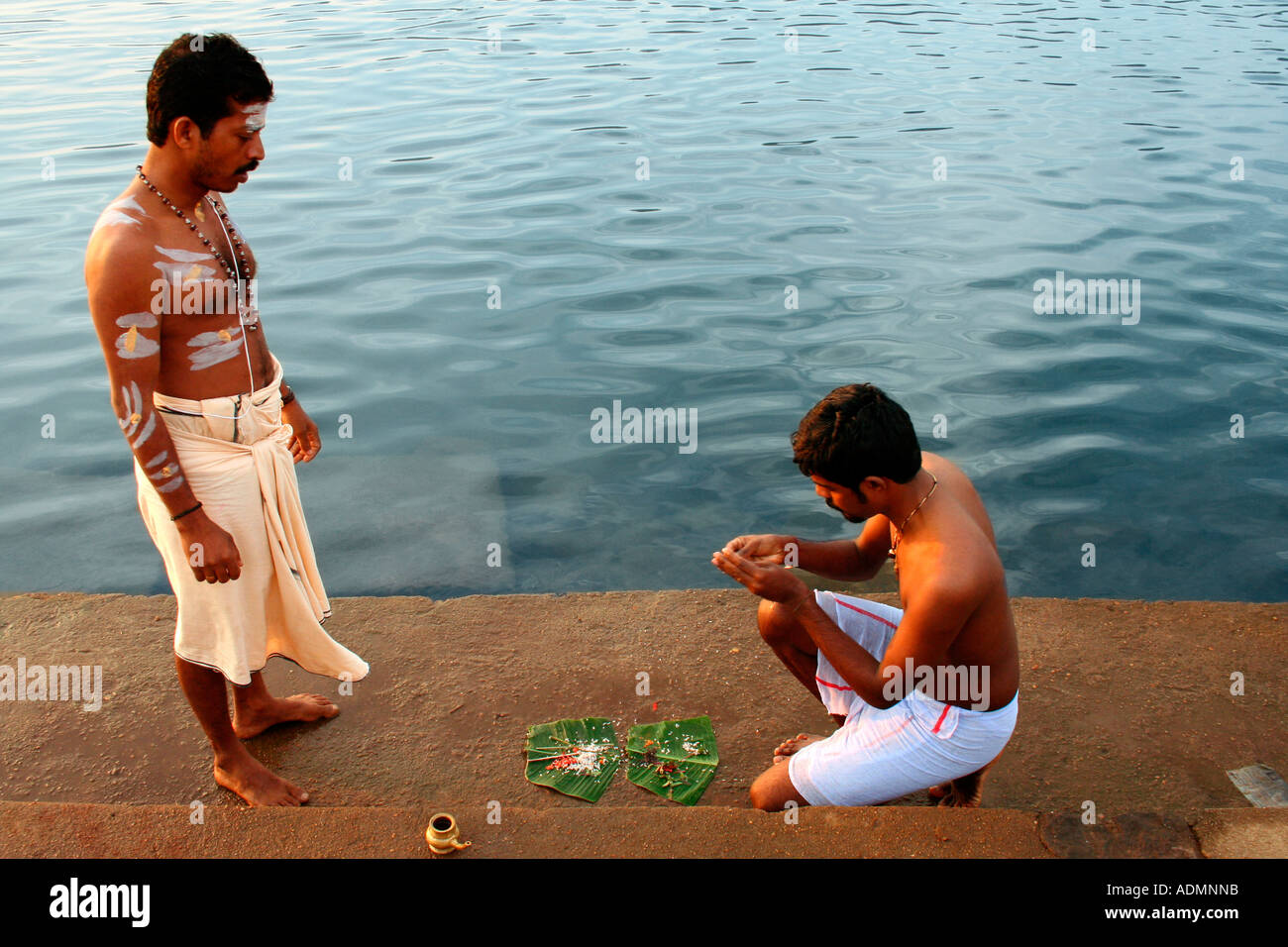 Uomo indù eseguendo pooja presso le rive del fiume del Periyar. Il sacerdote è dare istruzioni. Foto Stock