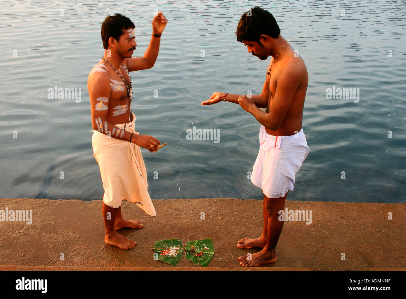 Uomo indù eseguendo pooja presso le rive del fiume del Periyar. Il sacerdote è dare istruzioni. Foto Stock