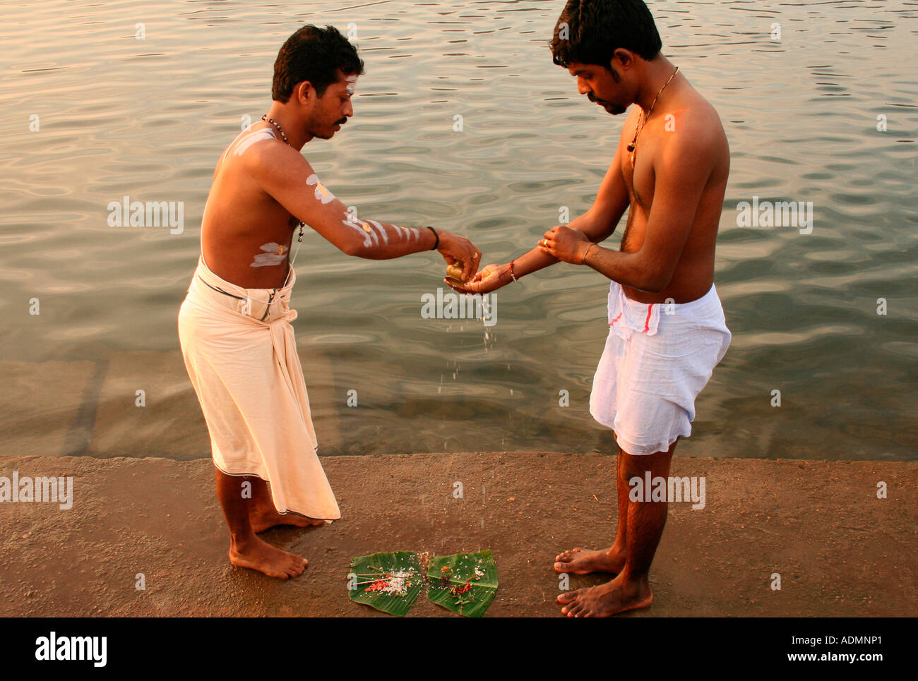 Uomo indù eseguendo pooja presso le rive del fiume del Periyar. Il sacerdote è dare istruzioni. Foto Stock