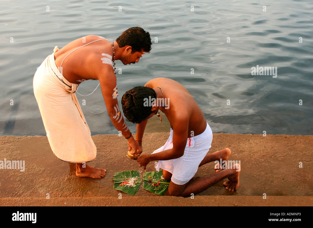 Uomo indù eseguendo pooja presso le rive del fiume del Periyar. Il sacerdote è dare istruzioni. Foto Stock