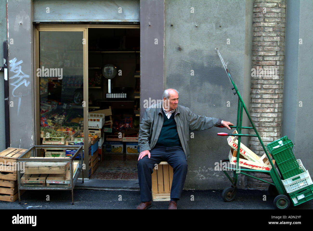 Uomo anziano in appoggio al di fuori di un negozio di frutta in una stradina a perugia umbria italia Foto Stock