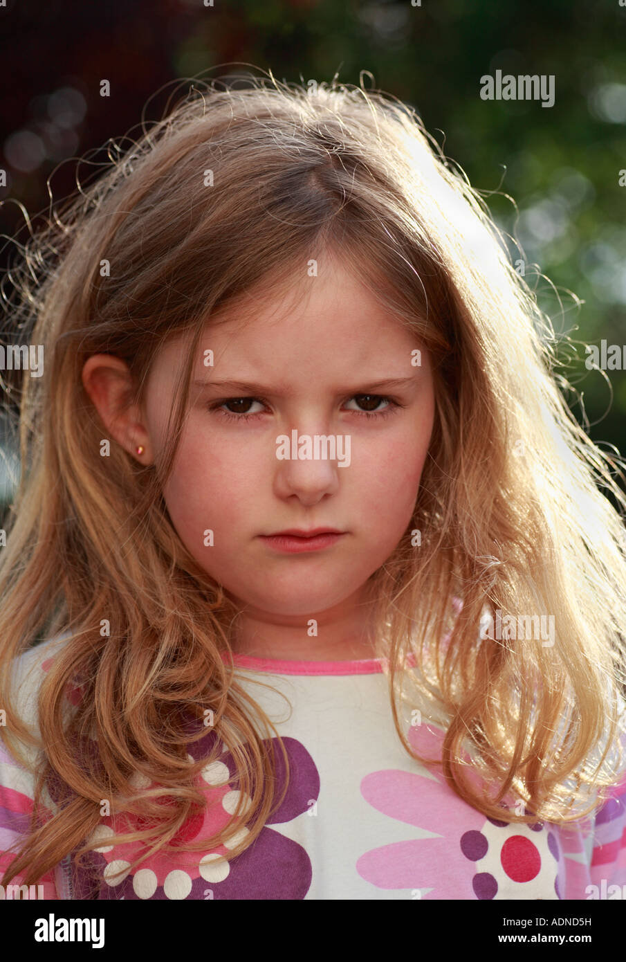 Testa e spalle shot di un 7 anno vecchia ragazza accigliata, in un cattivo umore o il broncio. Foto Stock