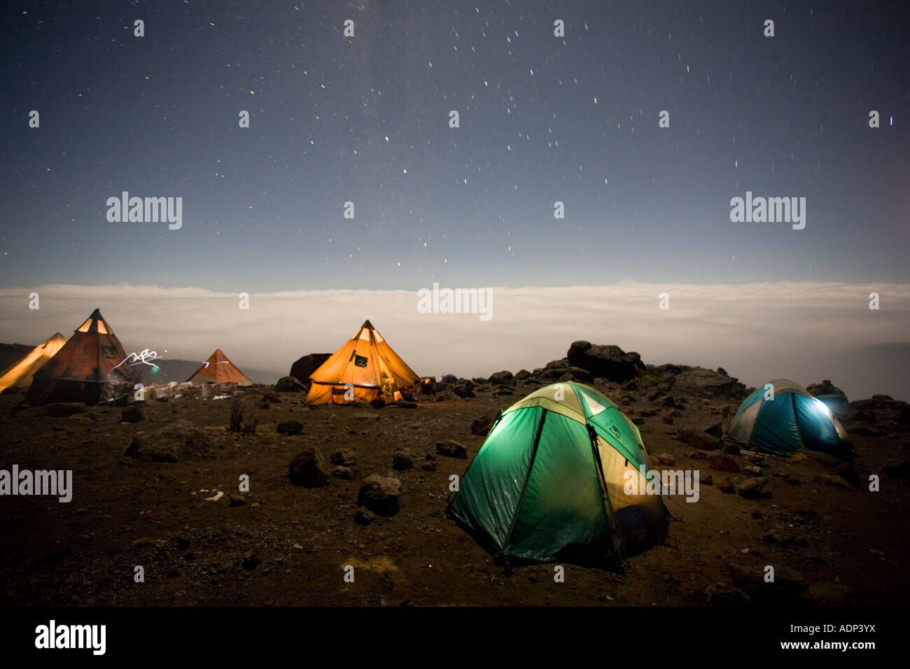 Africa Tanzania Parco Nazionale del Kilimanjaro Signor Arrampicata parti tende glow contro il cielo notturno a Karanga Camp Foto Stock