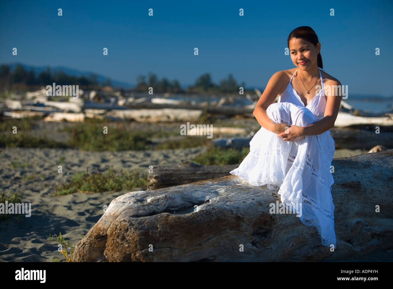 Donna seduta in spiaggia Foto Stock