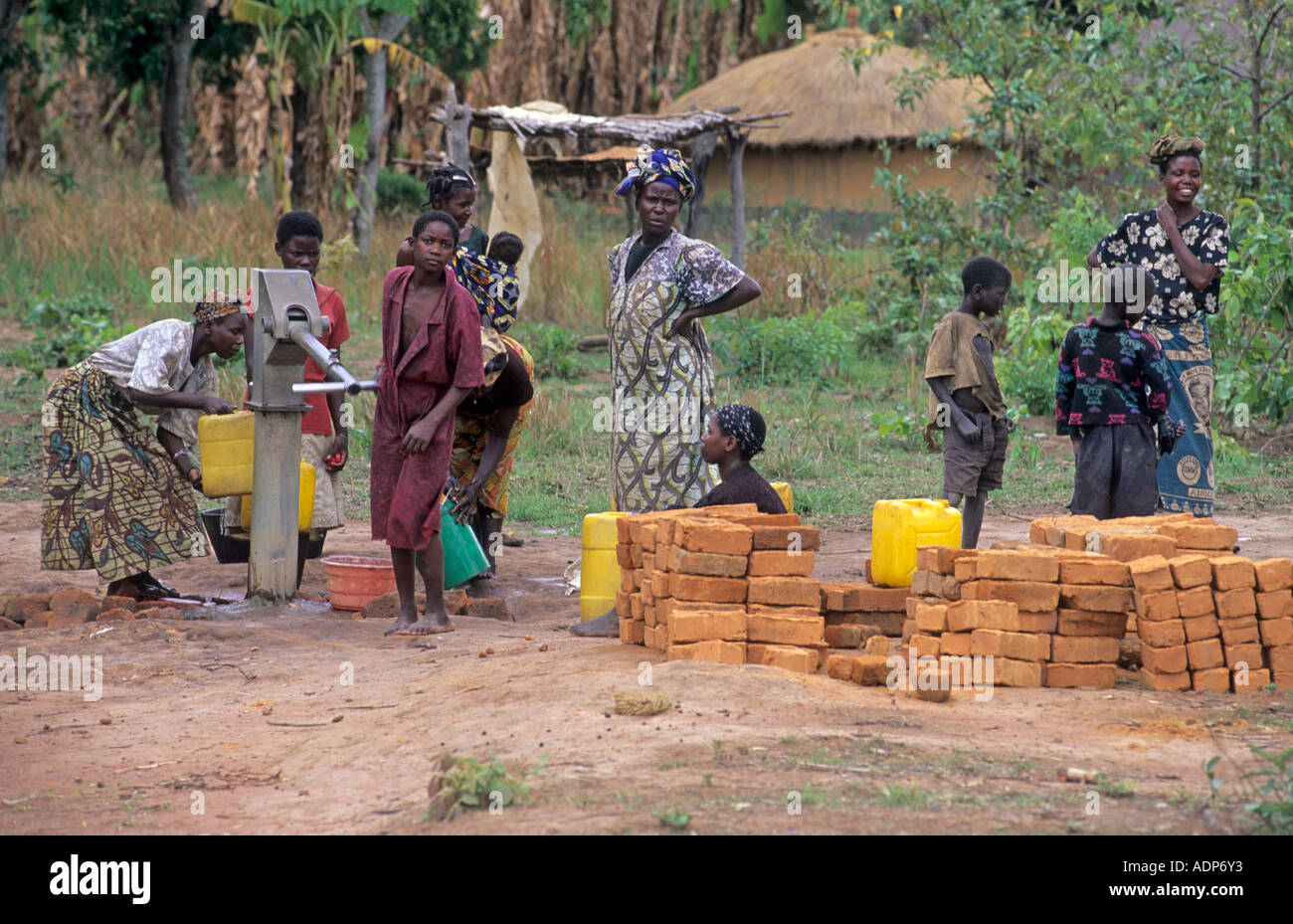 Le donne e i bambini di ottenere acqua da una pompa dell'acqua Zambia Foto Stock