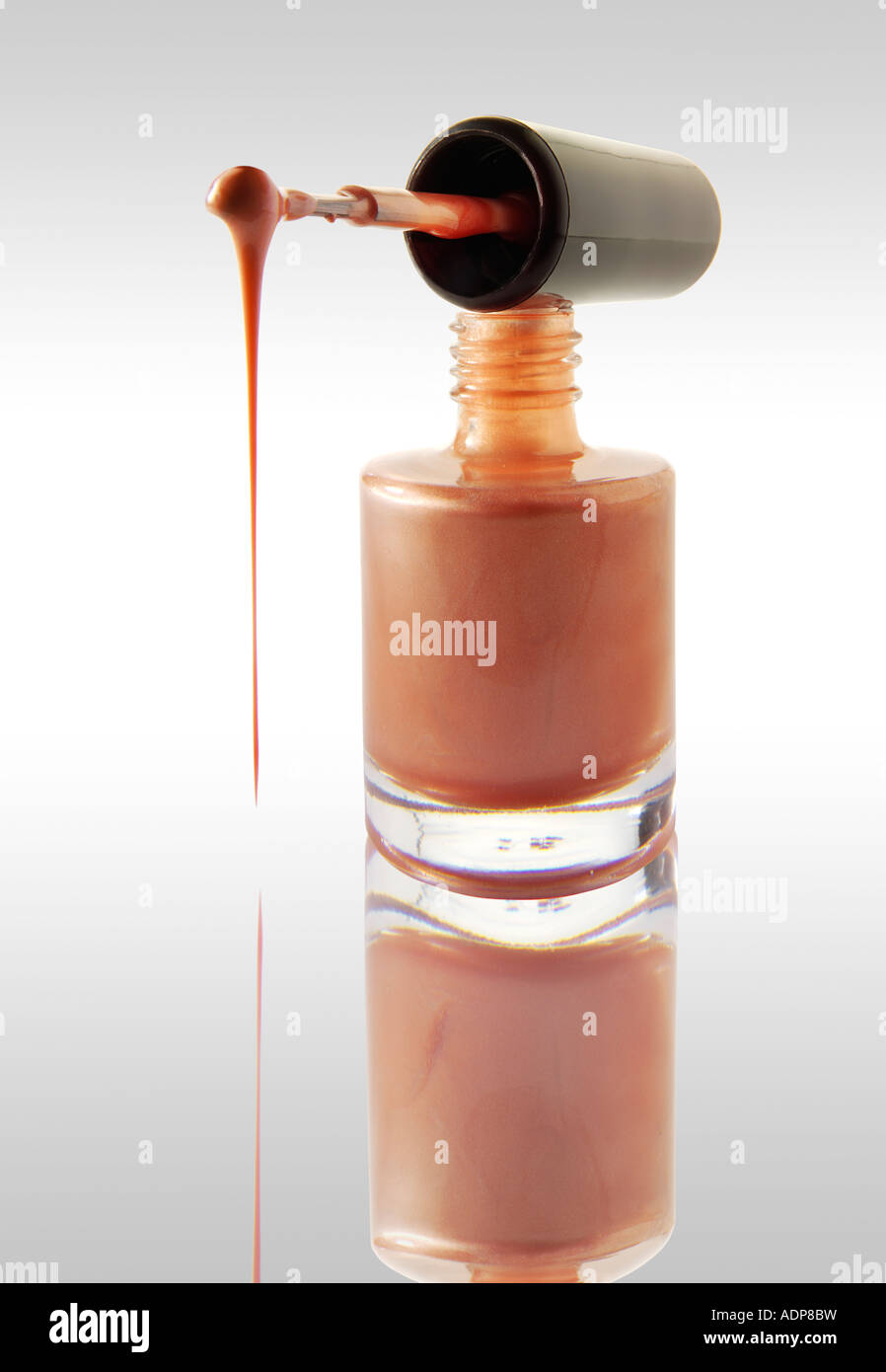 Smalto per unghie gocciolare da un smalto per unghie Spazzolino equilibrata su un chiodo del vaso di vernice rosa contro di colore bianco con una riflessione Foto Stock