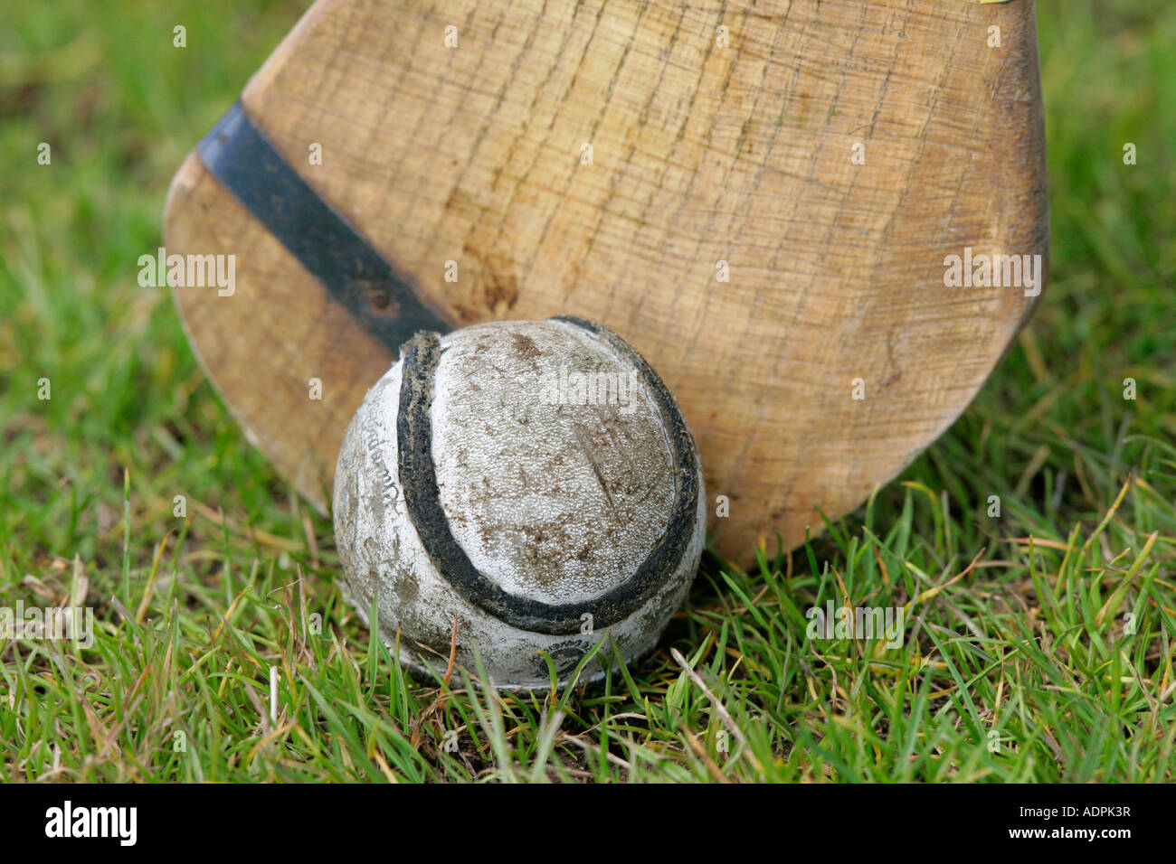 Utilizzato cuoio sliothar hockey irlandese sfera accanto alla testa del caman hurley stick sull'erba Foto Stock