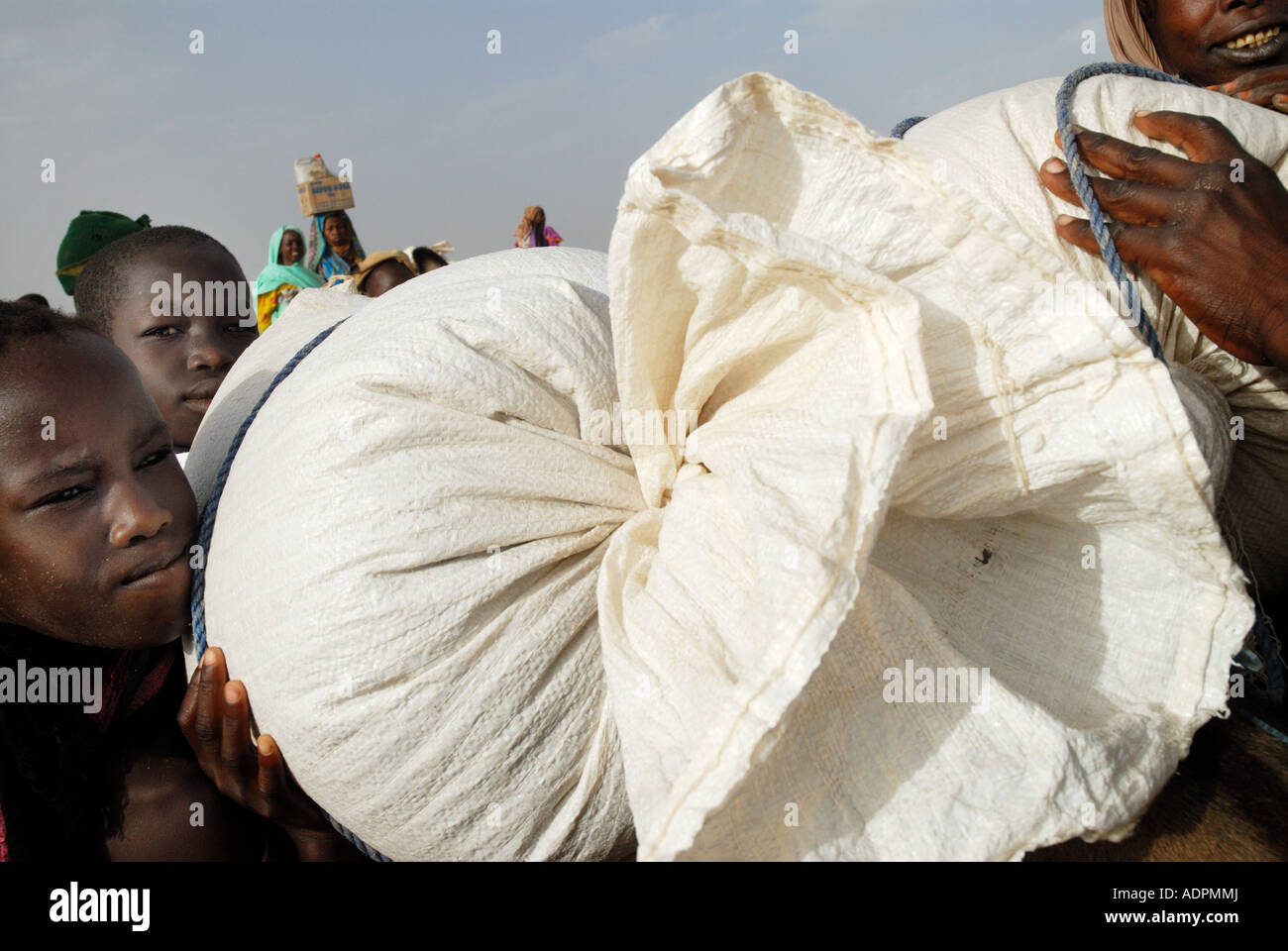 Africa.Ciad 2007 Bredjing camp per i profughi sudanesi .I bambini aiutano madre razioni di carico su Donkey. Foto Stock