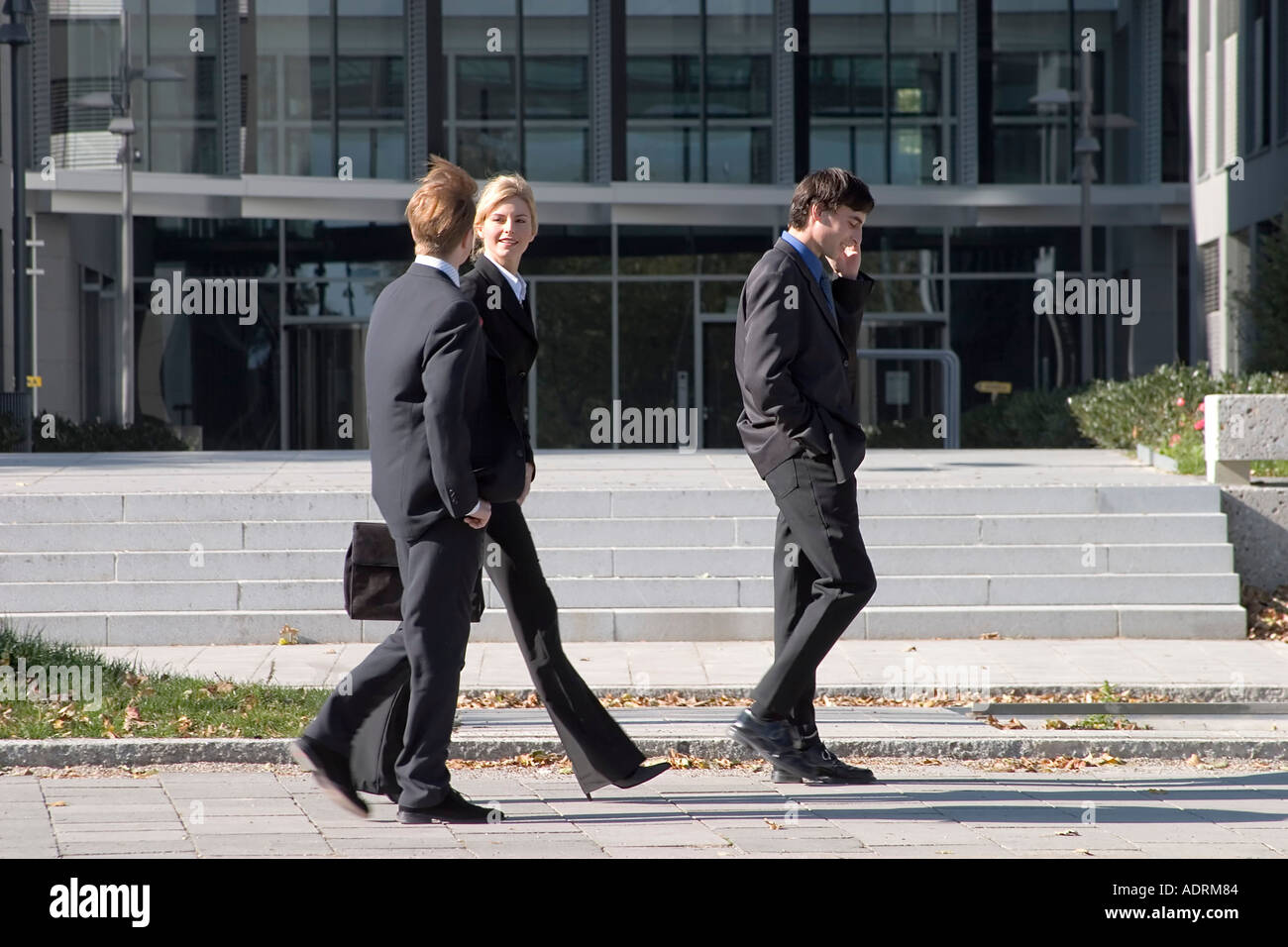 3 tre uomini di affari di passeggiare durante la pausa pranzo di fronte all edificio aziendale Foto Stock