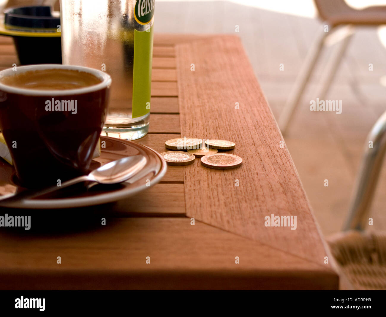 Una chiusura di una tazza di caffè e qualche euro su un tavolo del bar Foto Stock