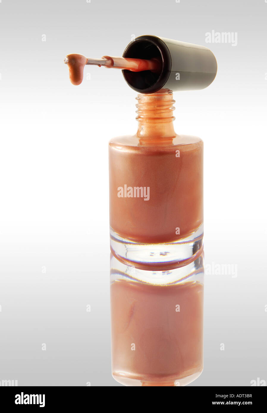Smalto per unghie gocciolare da un smalto per unghie Spazzolino equilibrata su un chiodo del vaso di vernice rosa contro di colore bianco con una riflessione Foto Stock