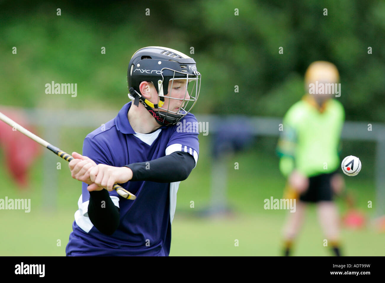 Ragazzo adolescente indossare casco protettivo altalene hockey irlandese bat caman a hurley sfera sliothar durante la pratica gioco Foto Stock
