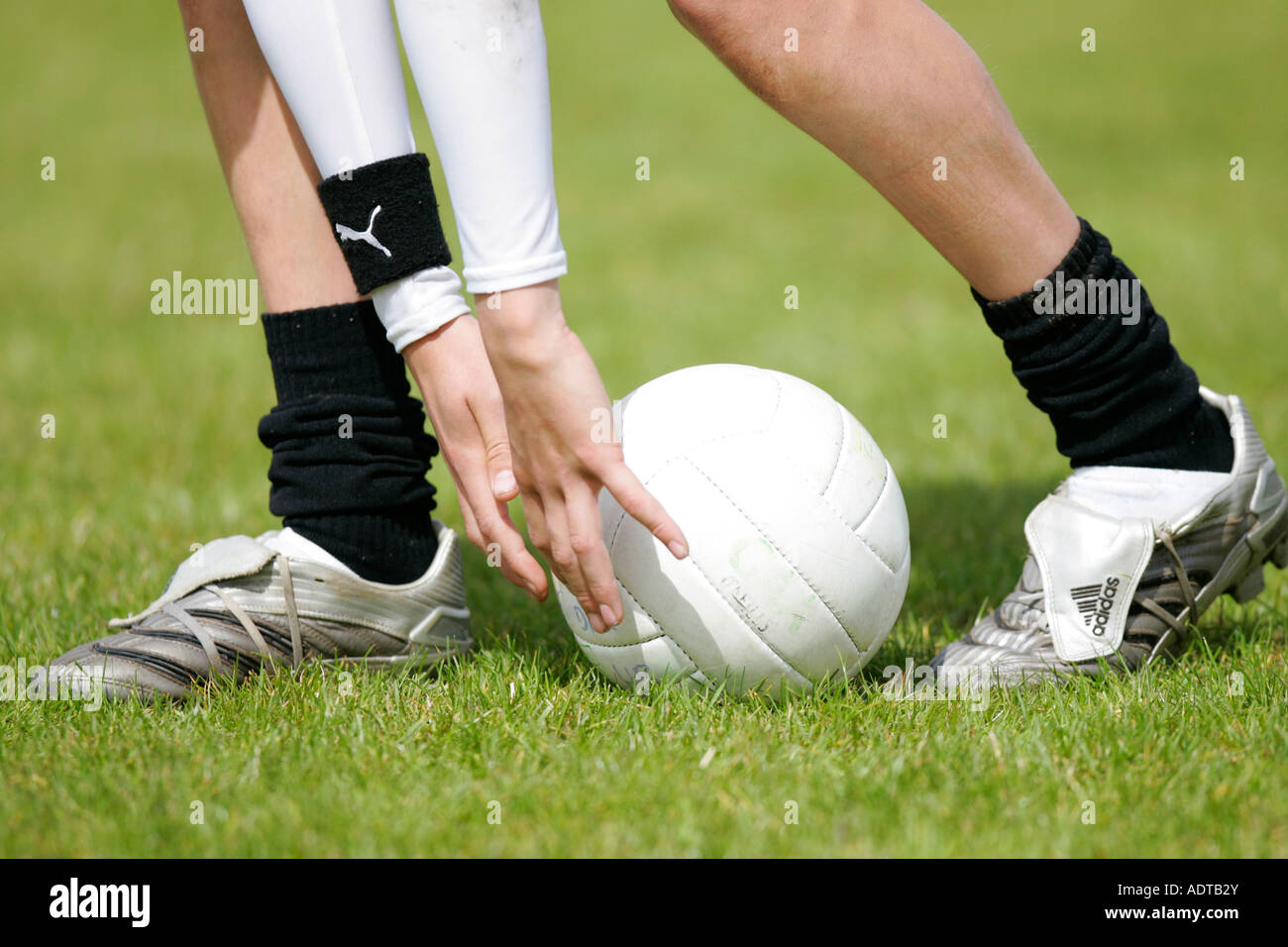 Ragazzo adolescente dimostra il modo tradizionale di prelevare il calcio in alto da terra durante il calcio gaelico gioco Foto Stock