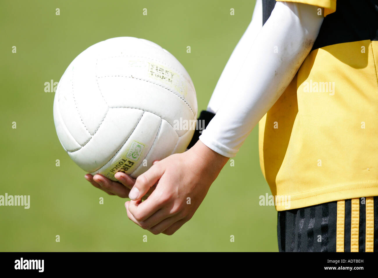 Ragazzo adolescente dimostra il modo tradizionale di mano passando il calcio gaelico durante la partita di calcio Foto Stock