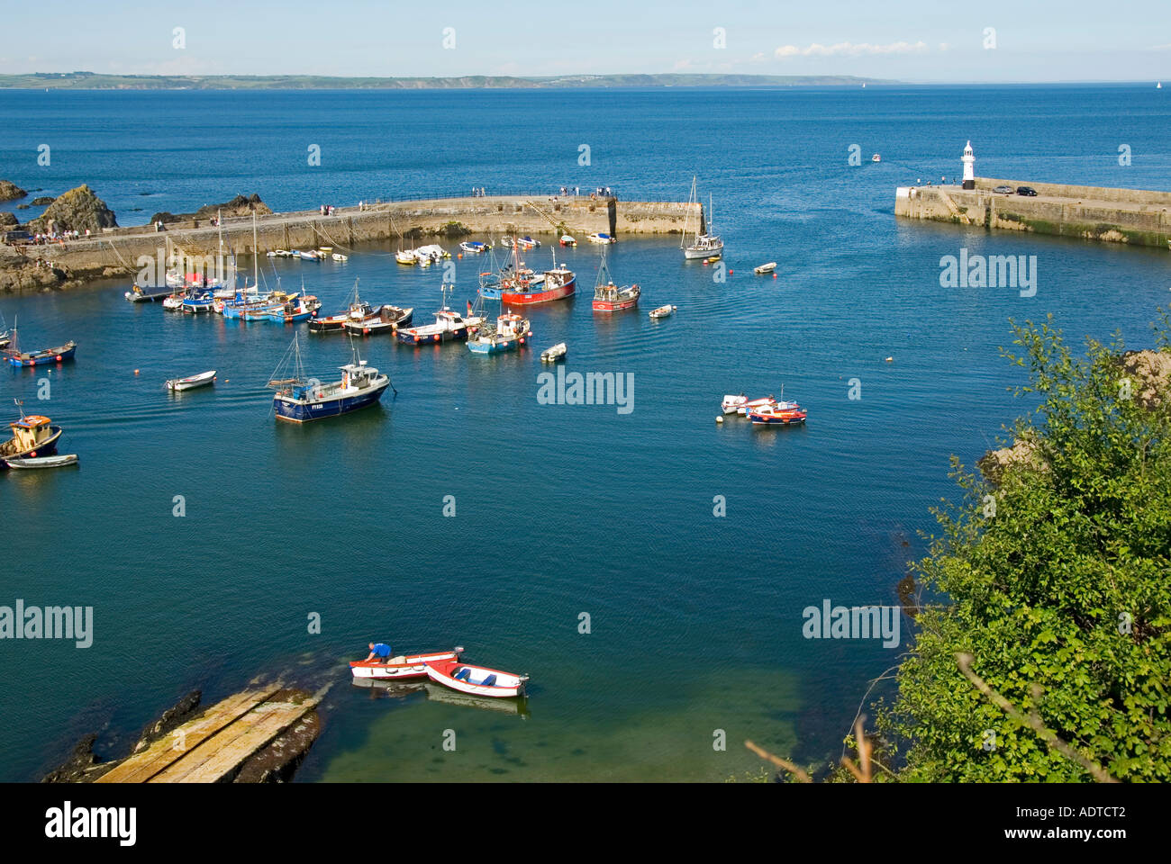 Mevagissey Cornish villaggio di pescatori guardando giù da sopra persone che camminano lungo il porto muro barca a ormeggio costa oltre Cornwall inglese UK Foto Stock