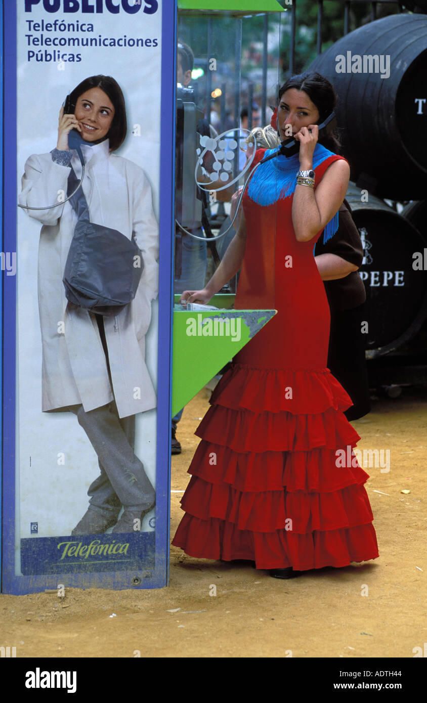 Siviglia una donna in abiti di flamenco effettuando una telefonata ad un telefono pubblico a feria de abril Foto Stock