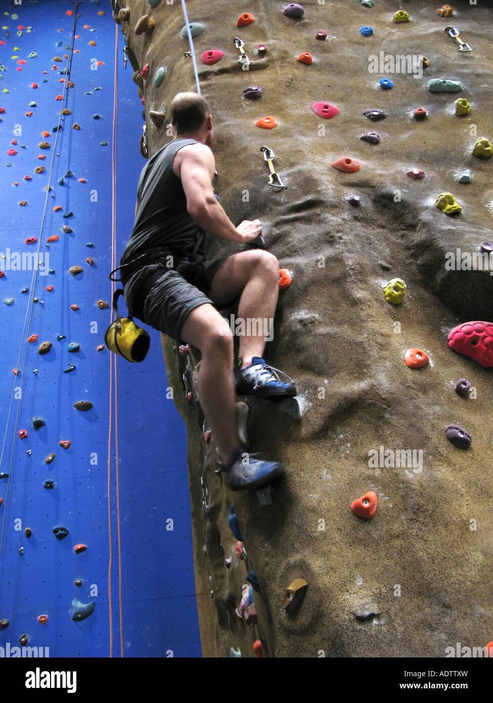 Un unico maschio bianco arrampicata su una piscina parete di arrampicata percorso. Foto Stock