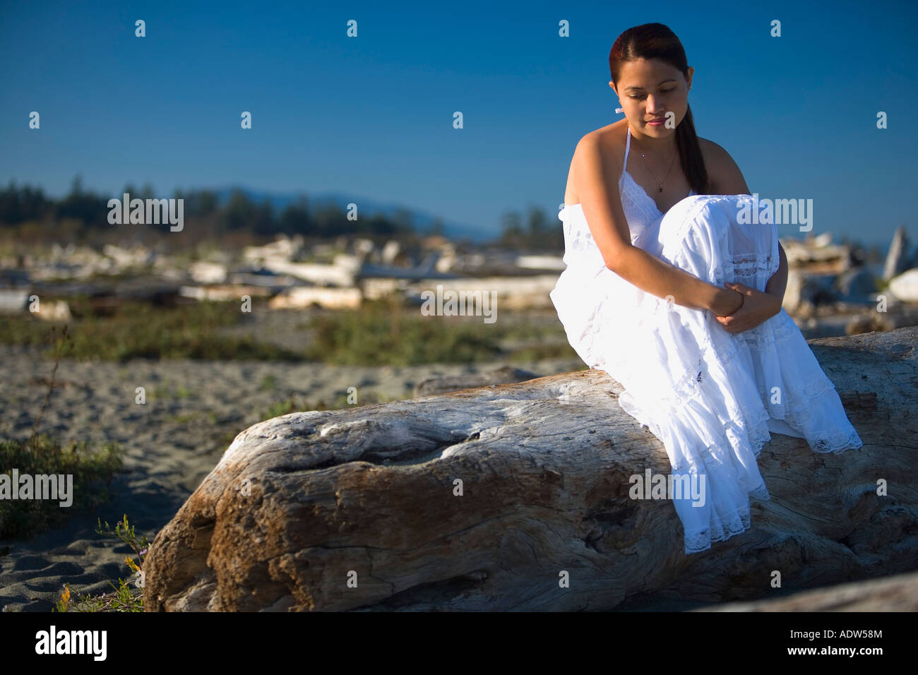 Donna seduta in spiaggia Foto Stock