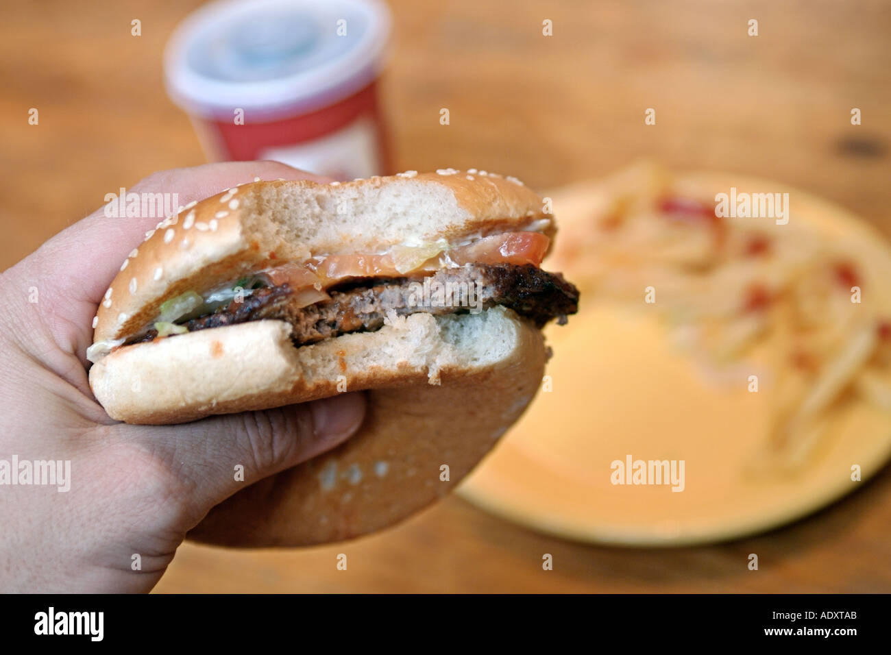 Close-up di un semi-mangiato hamburger in una mano d'uomo. Foto Stock