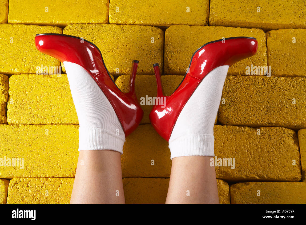 Scarpe rosse sui mattoni di colore giallo Foto Stock