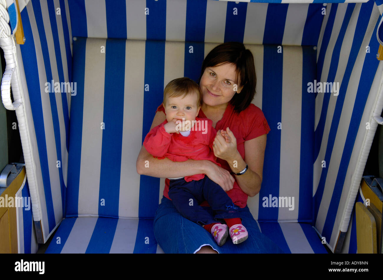 Madre e figlia seduti sulla spiaggia mobili Foto Stock
