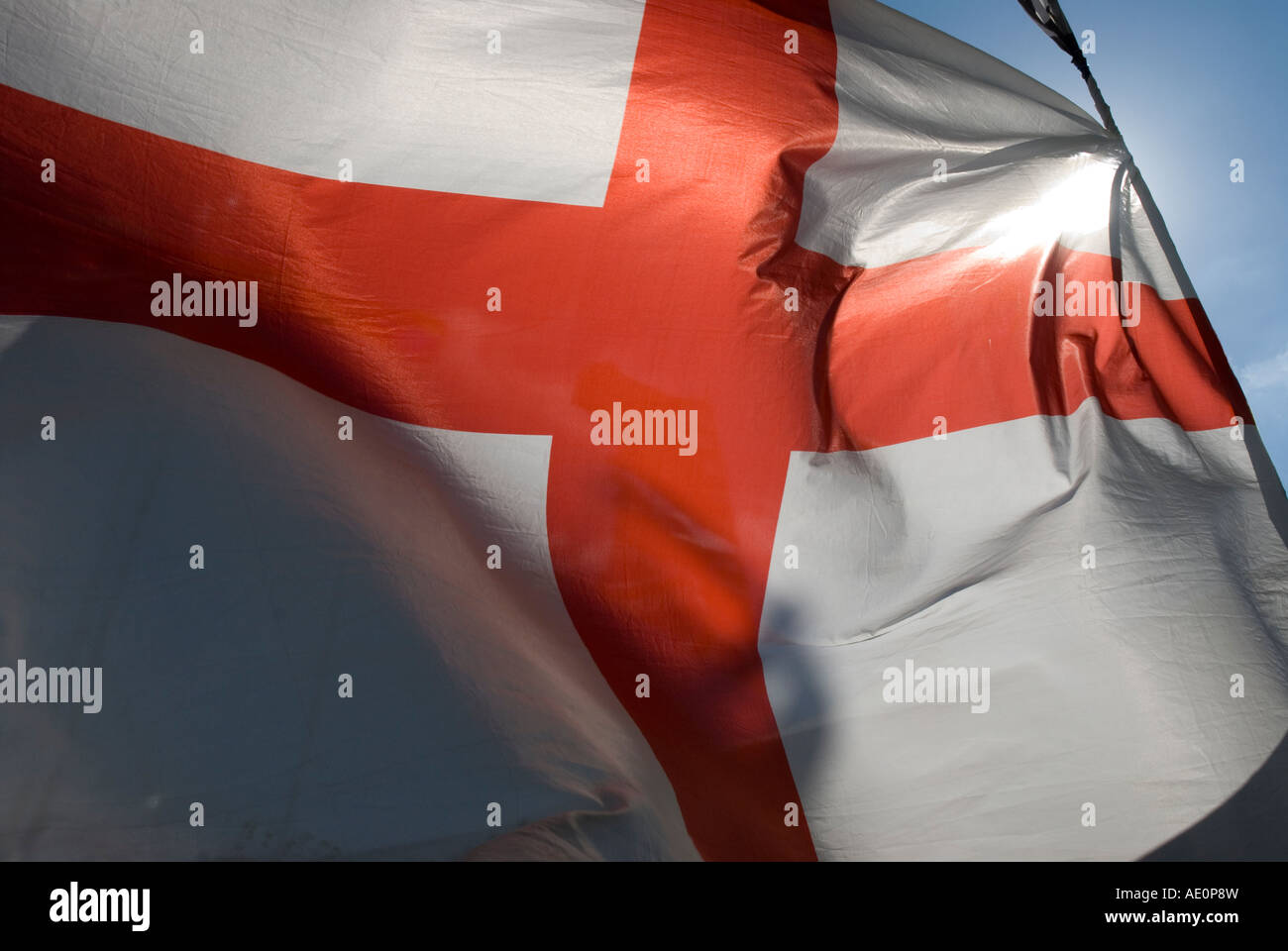 St Georges battenti bandiera nel vento con il sole dietro di essa Foto Stock