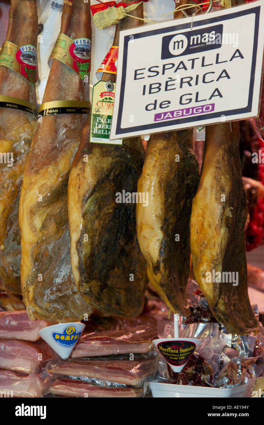 Appendere su garretti prosciutto cotto nel mercato coperto La Boqueria a La Rambla, Barcelona Spagna Foto Stock