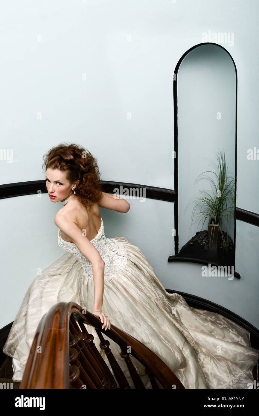 Una bella sposa scende giù per una scalinata che indossa un abito di sartoria. Foto Stock