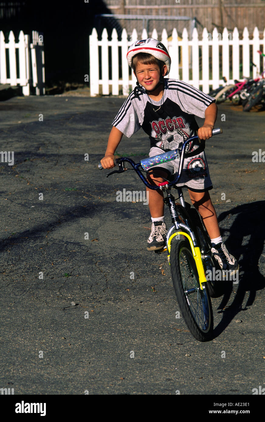 Un ragazzo indossa un casco di sicurezza come cavalca la sua bicicletta Foto Stock