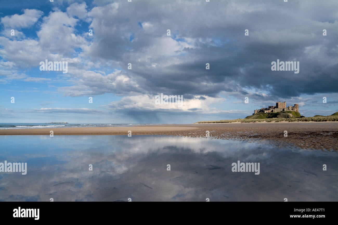 Riflessi del cielo e il castello di Bamburgh sulla spiaggia Bamburgh, Northumberland, Regno Unito Foto Stock