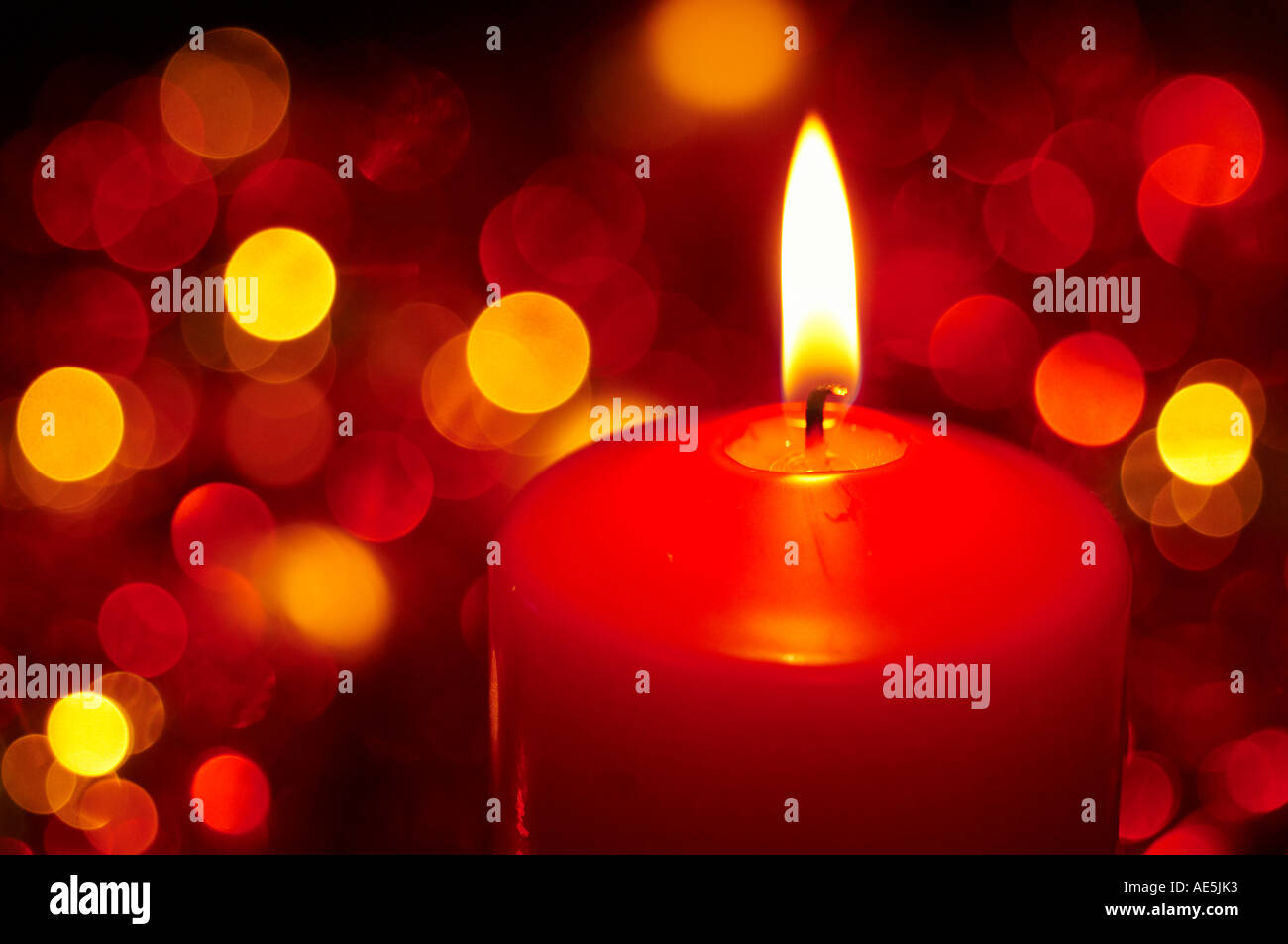 Una candela rossa masterizzazione con fuori fuoco le luci fairy in background. Foto Stock
