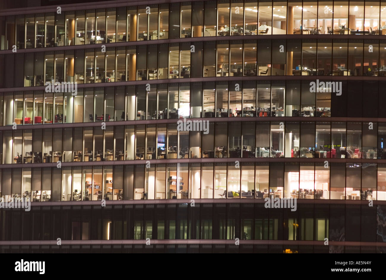 Diversi piani di costruzione di ufficio visto dall'esterno attraverso finestre di vetro di notte Foto Stock