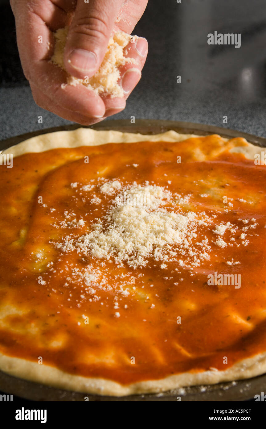 L'uomo spolverata formaggio sulla pizza Foto Stock